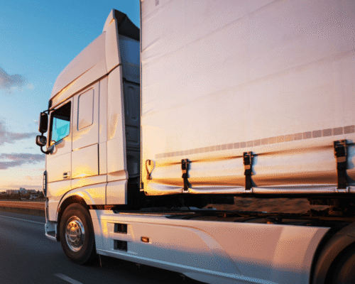 A large commercial truck drives down the highway at sunset, representing the trucking industry in Texas. The image supports a legal blog explaining how Electronic Logging Device (ELD) compliance failures can contribute to big rig accidents in Dallas and what legal options are available for victims.
