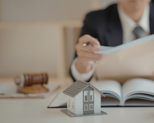 Landlord or attorney reviewing apartment property documents with model home and gavel, illustrating how to prove landlord negligence in a Dallas apartment injury claim involving unsafe conditions and premises liability.