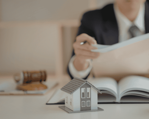 Landlord or attorney reviewing apartment property documents with model home and gavel, illustrating how to prove landlord negligence in a Dallas apartment injury claim involving unsafe conditions and premises liability.